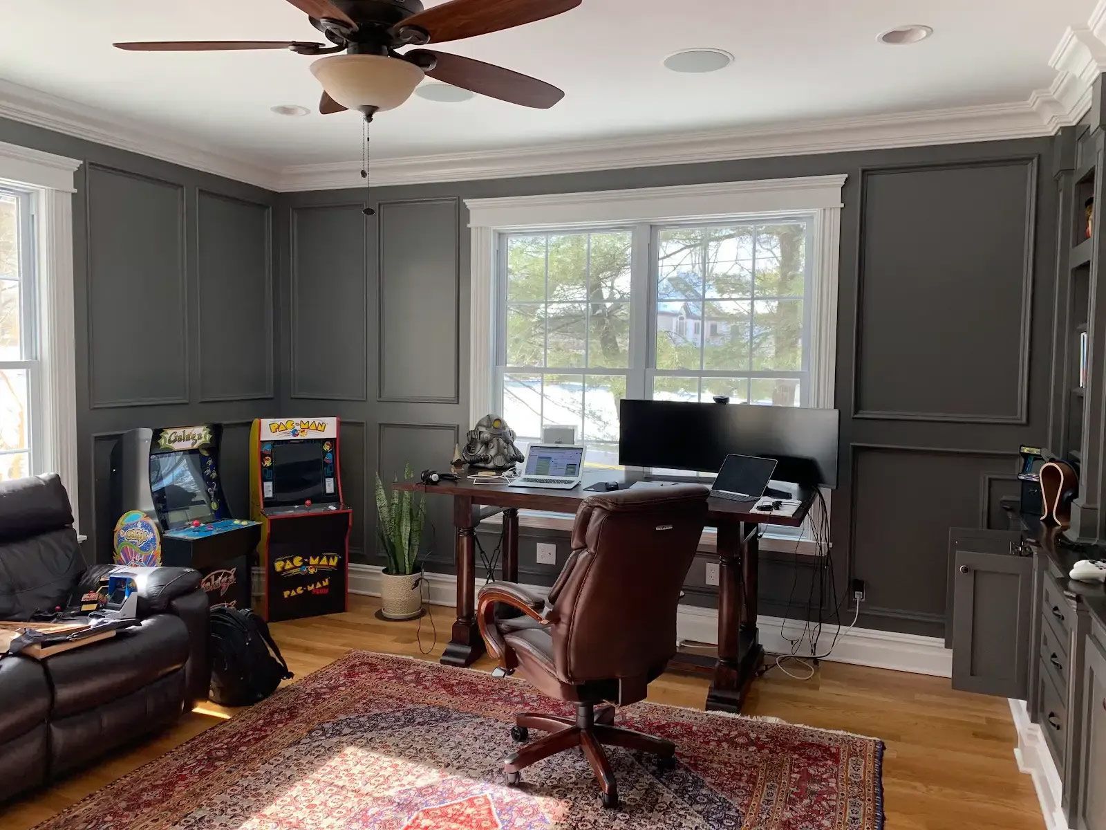 A living room with a couch, desk, chair and a ceiling fan
