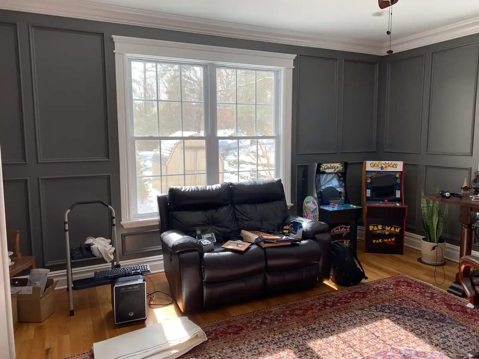 A living room with a couch, arcade machine, and a window