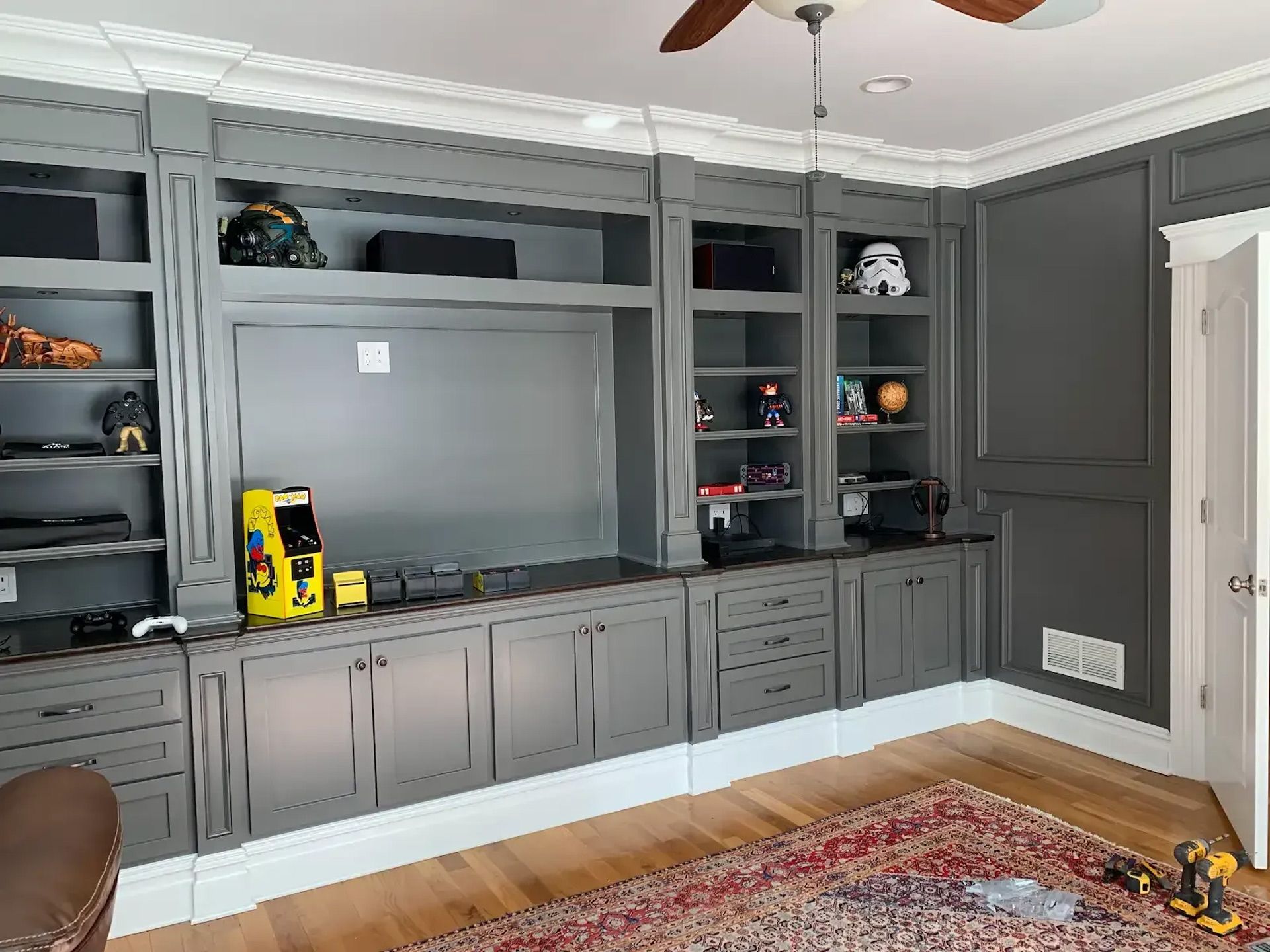 A living room with a lot of cabinets and shelves and a ceiling fan