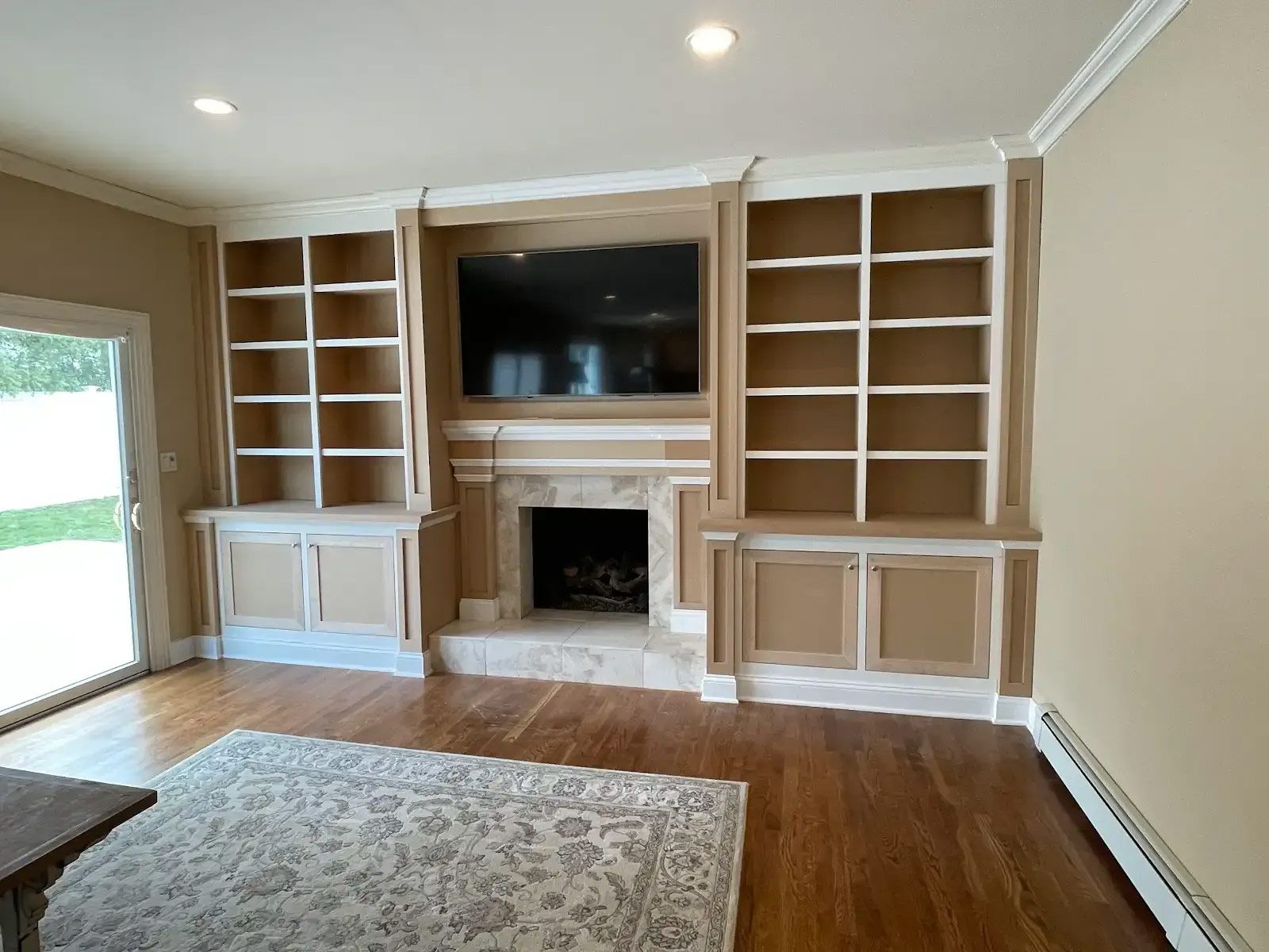 A living room with a fireplace, shelves, and a flat screen tv