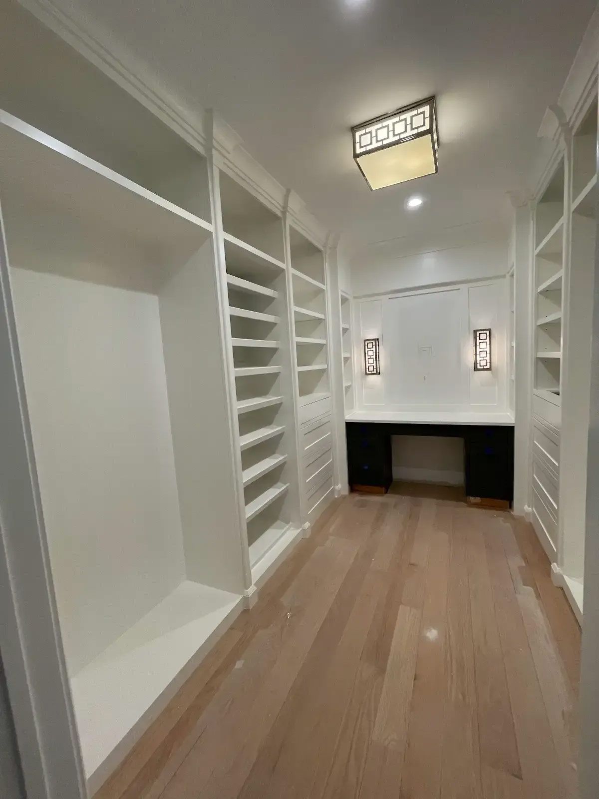 A walk in closet with lots of shelves and a desk