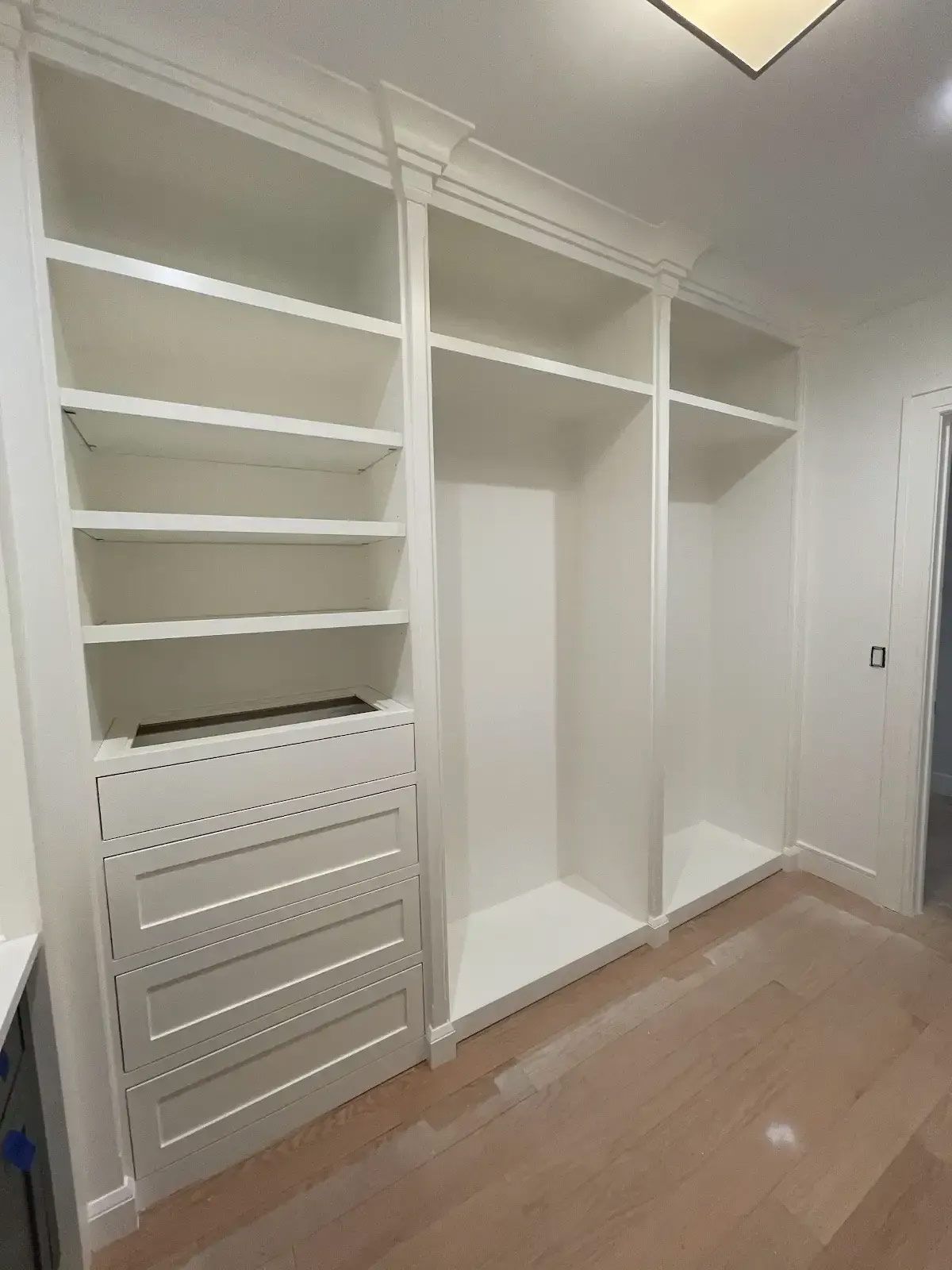 A walk in closet with lots of shelves and drawers