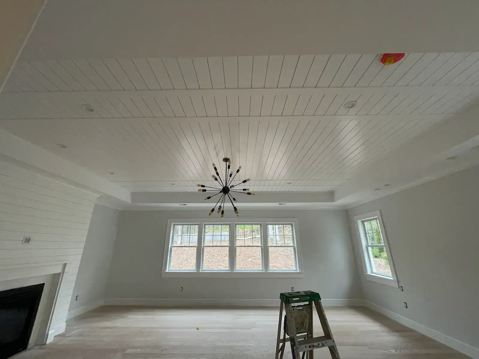 A living room with a ladder and a chandelier hanging from the ceiling