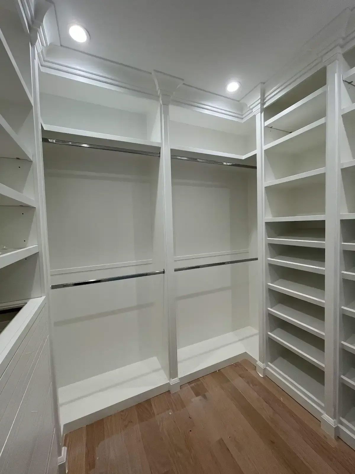 A walk in closet with lots of shelves and clothes racks