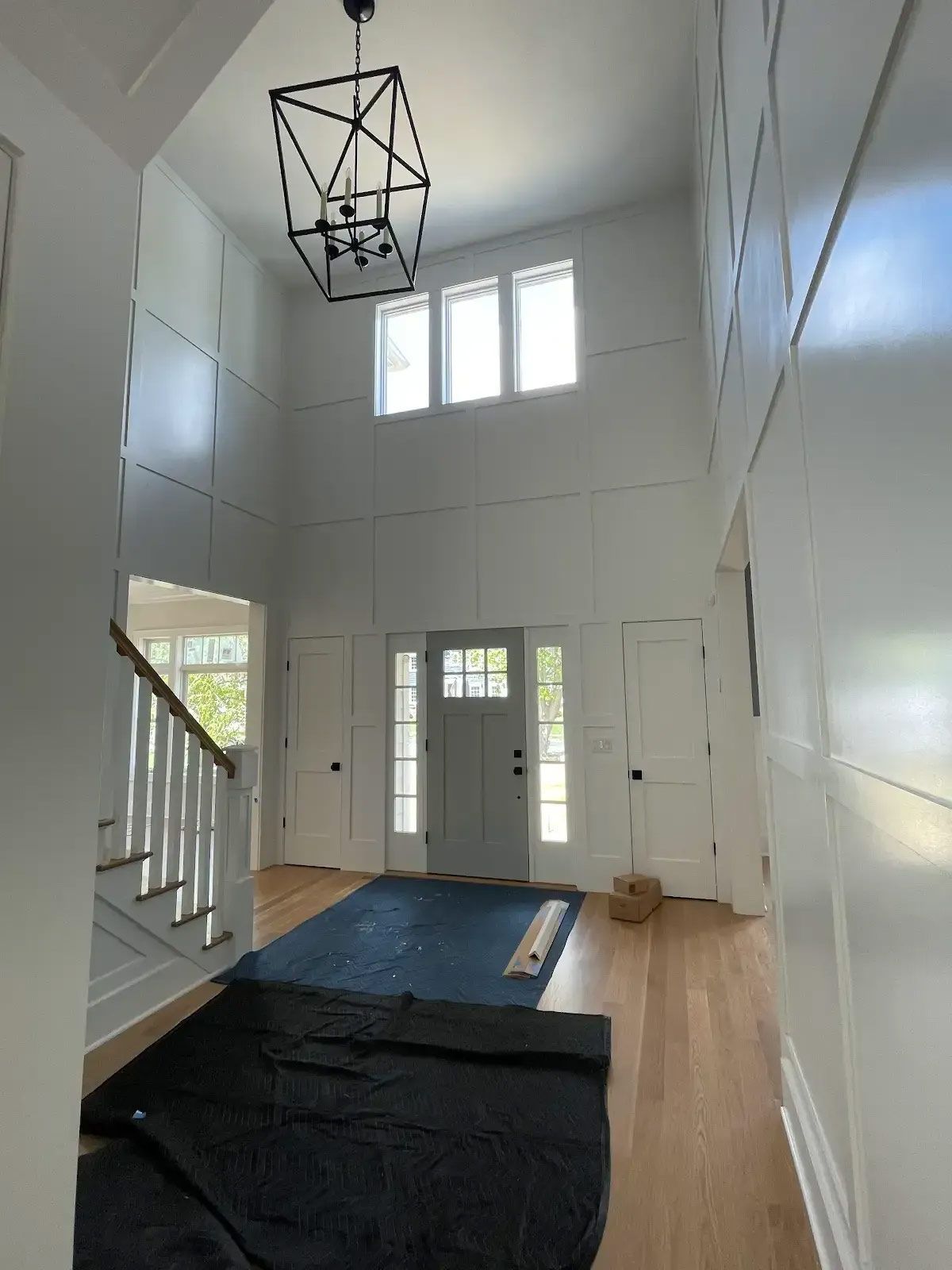 A large hallway with a staircase and a chandelier hanging from the ceiling