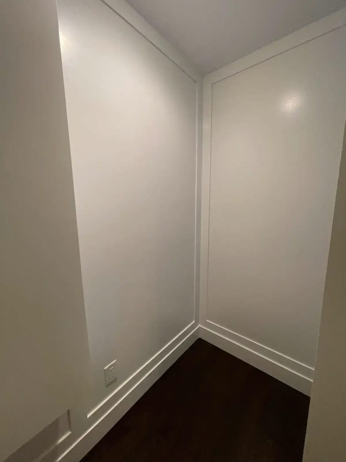 An empty room with white walls and a brown floor