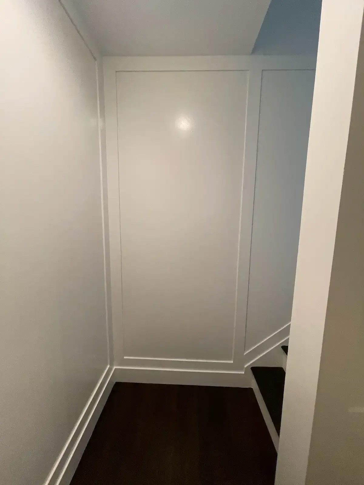 A hallway with stairs and a white wall