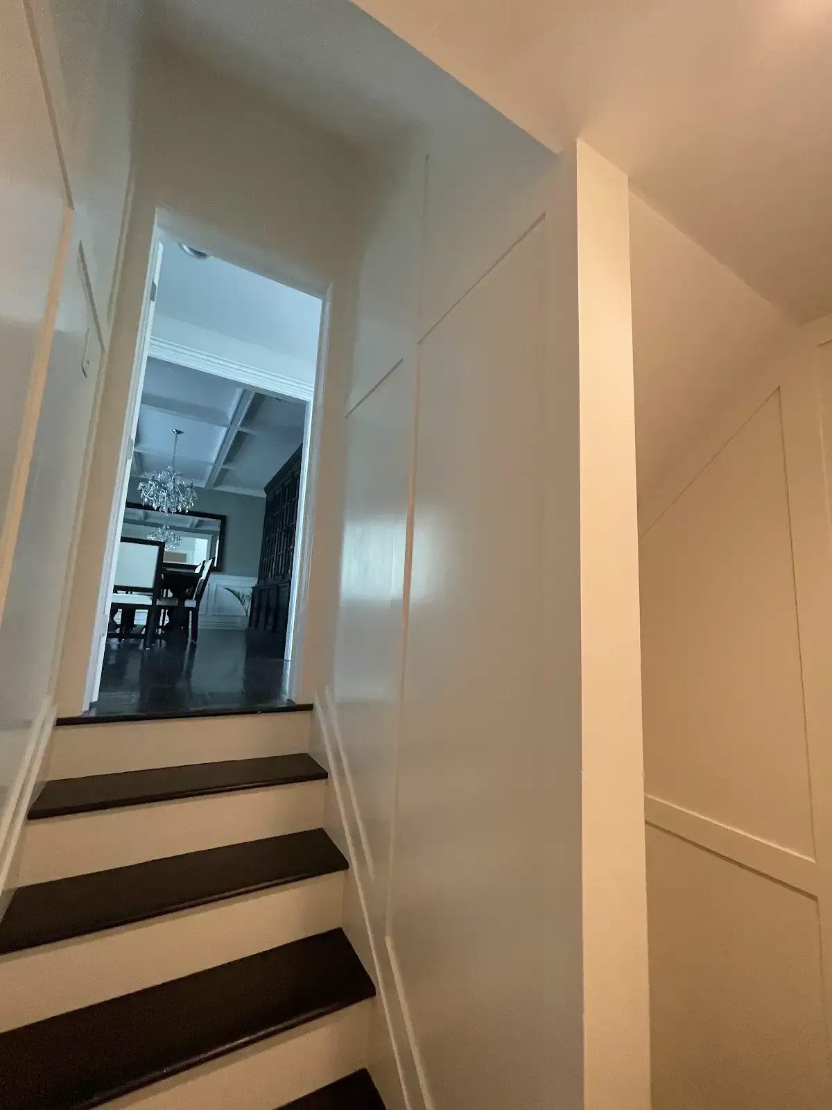 A hallway with stairs leading up to a dining room in a house