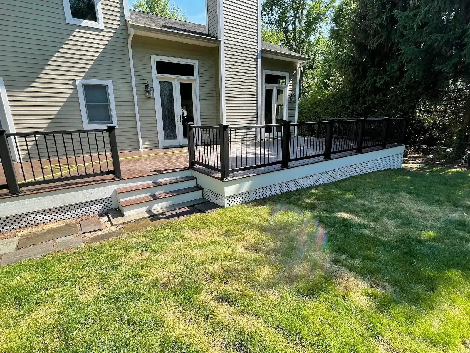 A large deck with stairs leading up to it is in the backyard of a house