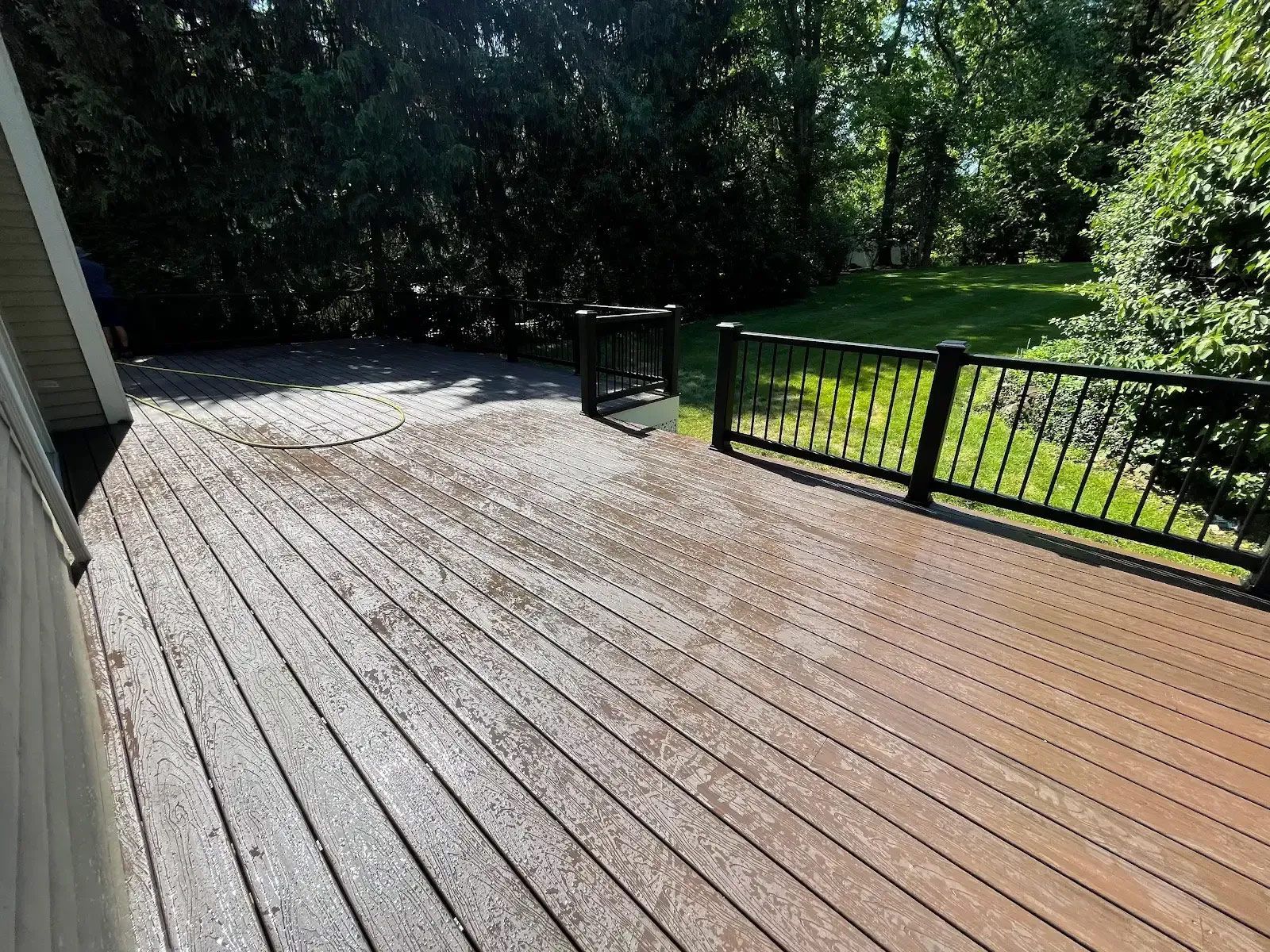 A wooden deck with a metal railing and trees in the background