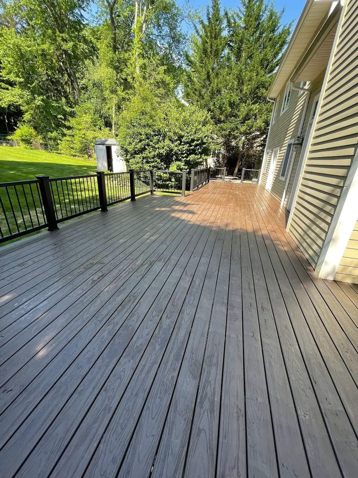 A large wooden deck with a fence and trees in the background
