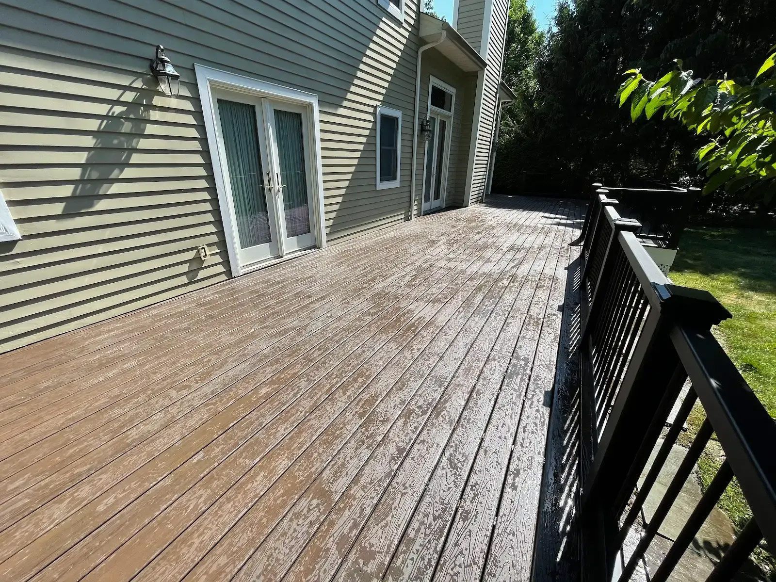 A large wooden deck with a railing in front of a house