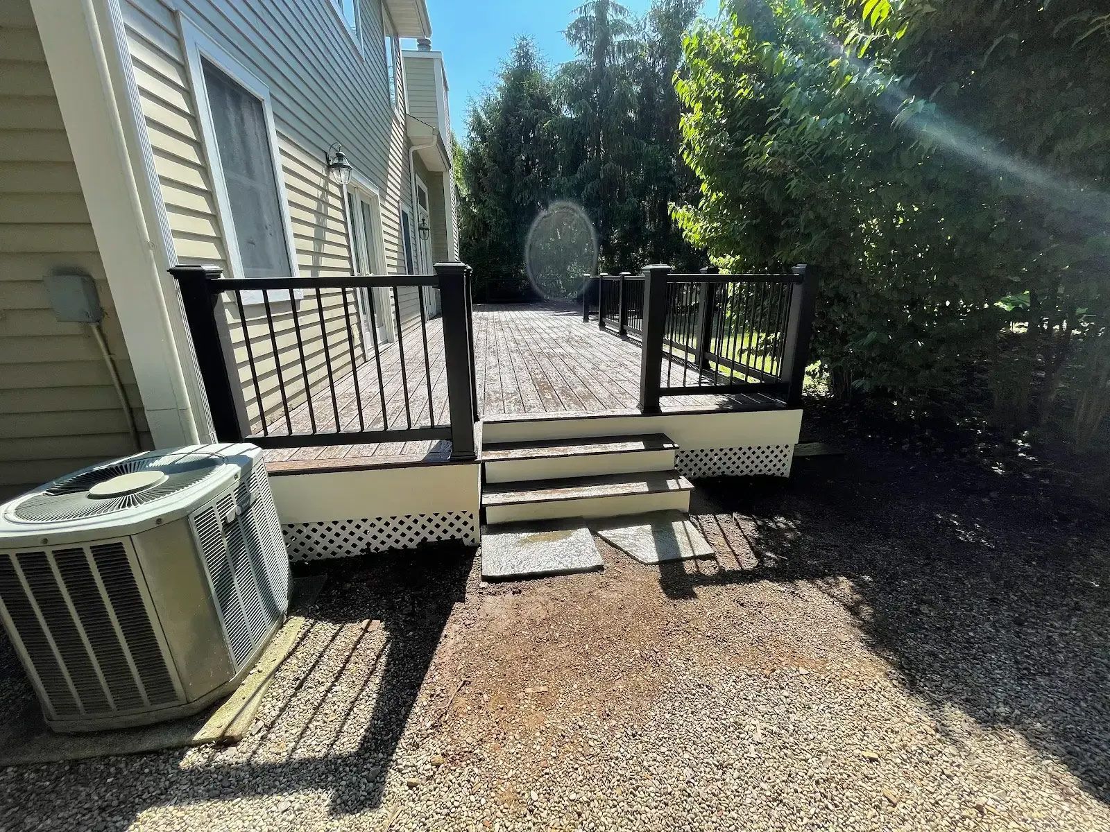 There is a deck with stairs and a air conditioner in the backyard