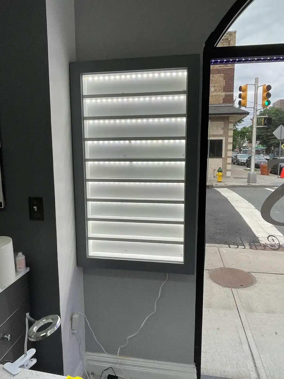 A picture of a wall with a light on it and a street in the background