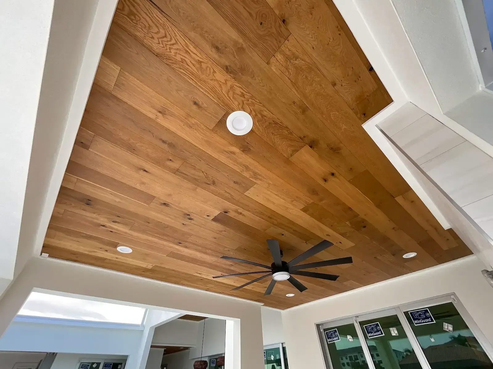 A wooden ceiling with a ceiling fan in a room