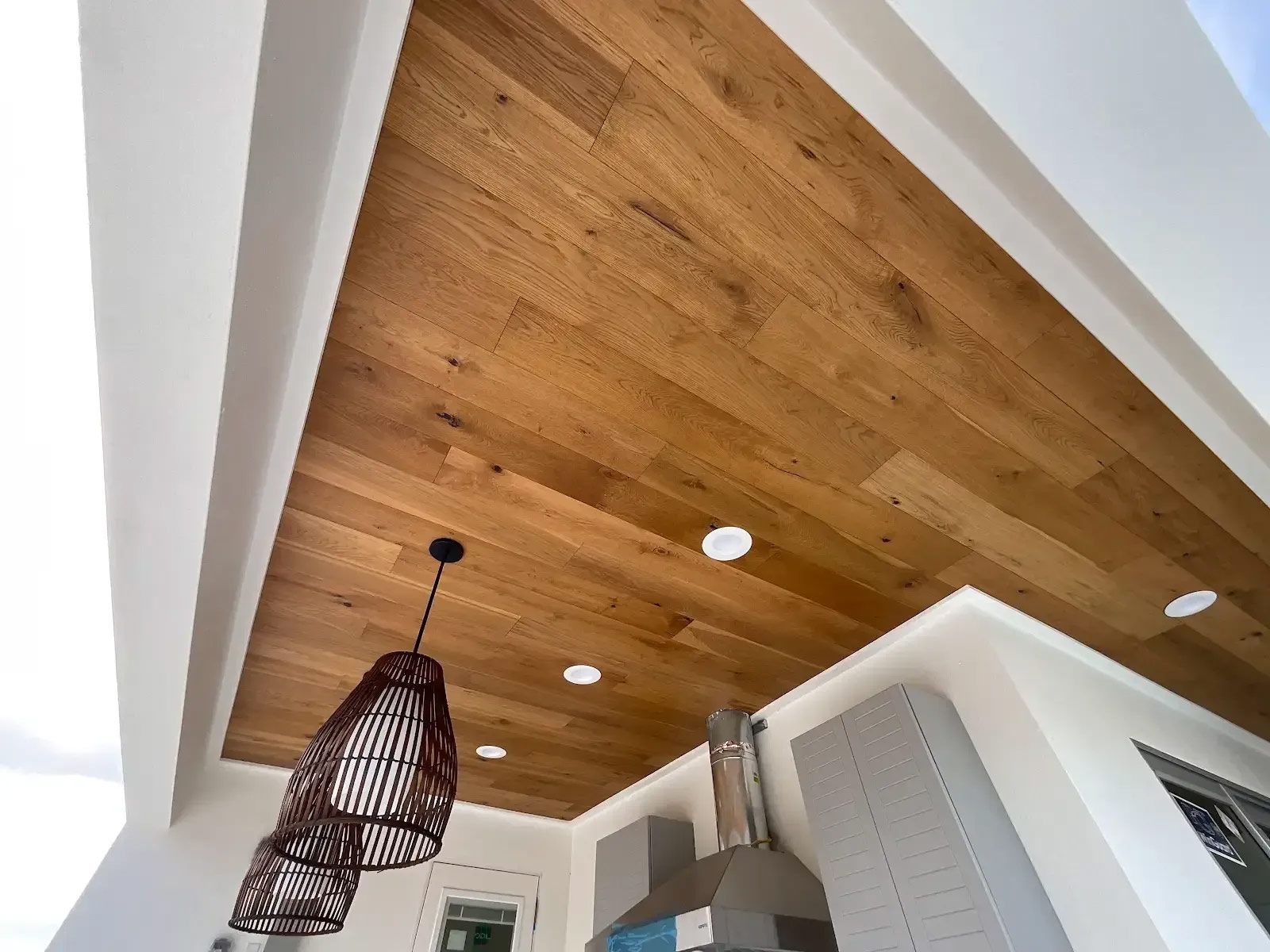 A kitchen with a wooden ceiling and a pendant light