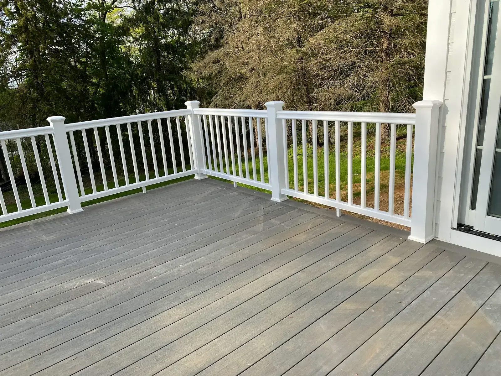A deck with a white railing and a sliding glass door