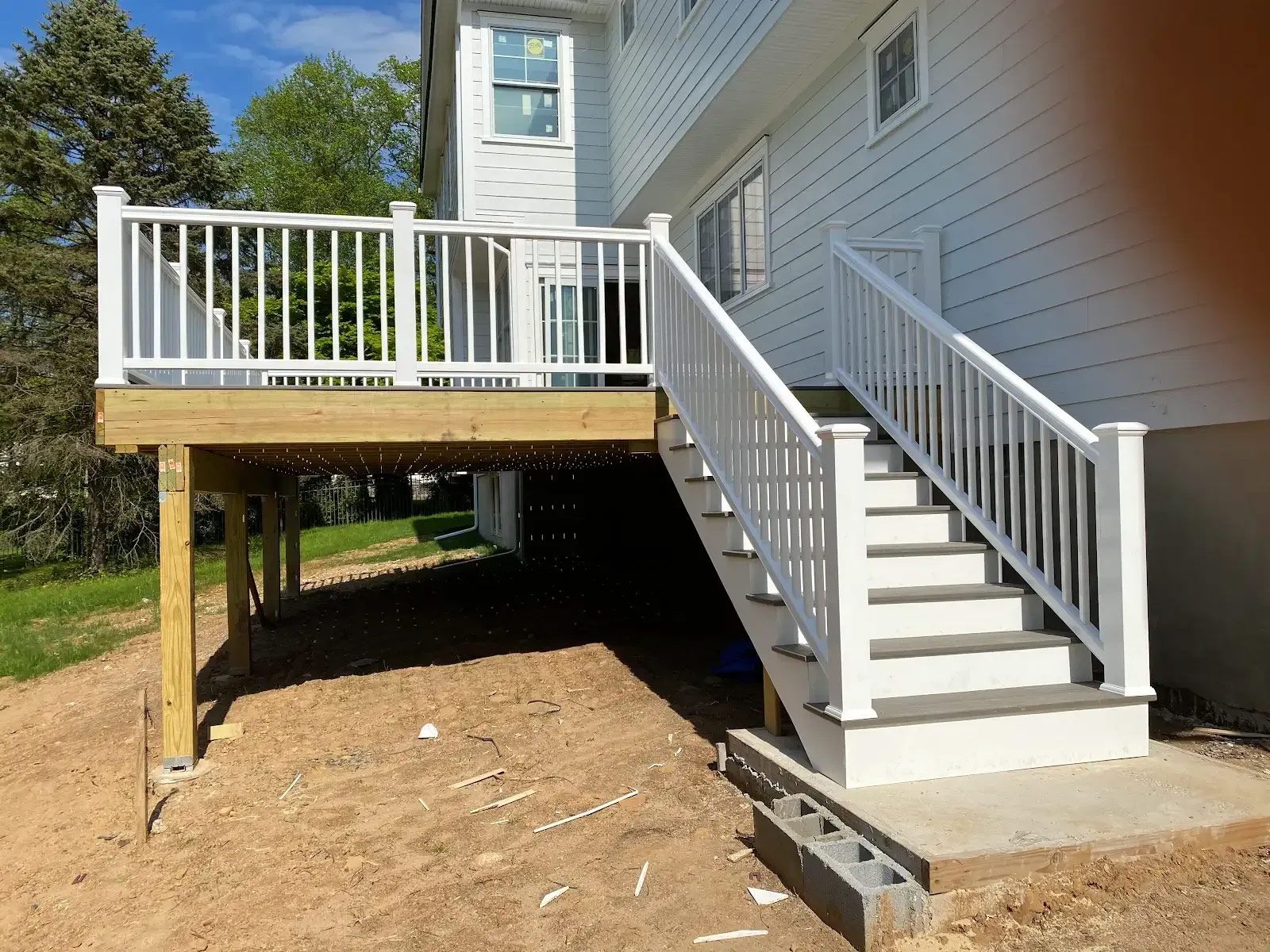 A white house with a wooden deck and stairs