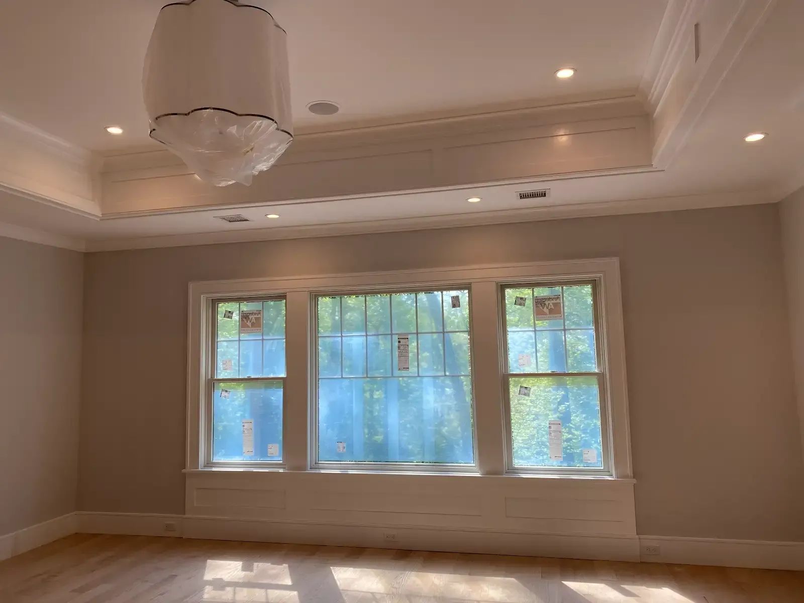An empty room with three windows and a chandelier hanging from the ceiling