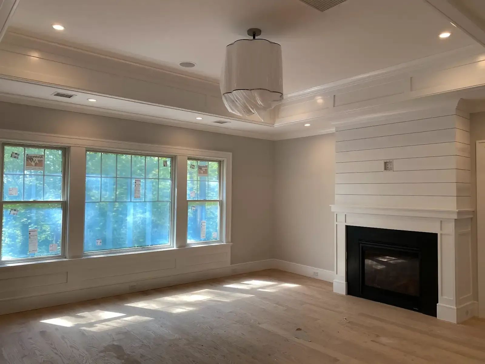 An empty living room with a fireplace and lots of windows