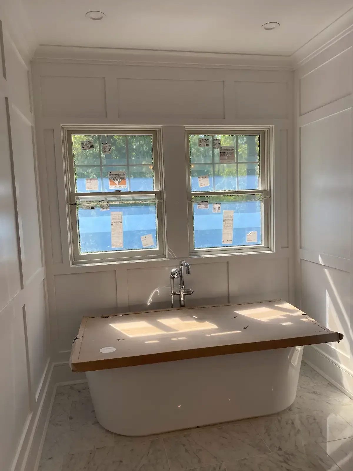 A bathroom with a bathtub and two windows