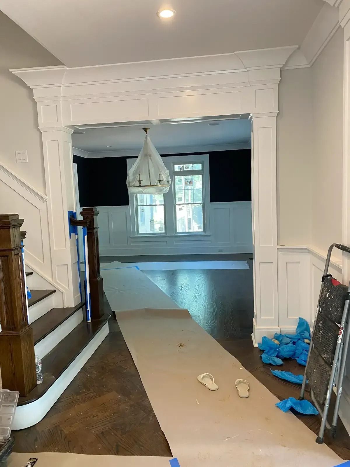 A hallway leading to a living room with stairs and a chandelier
