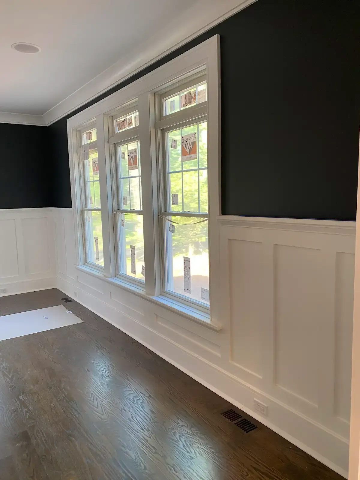An empty room with black walls and white trim and windows