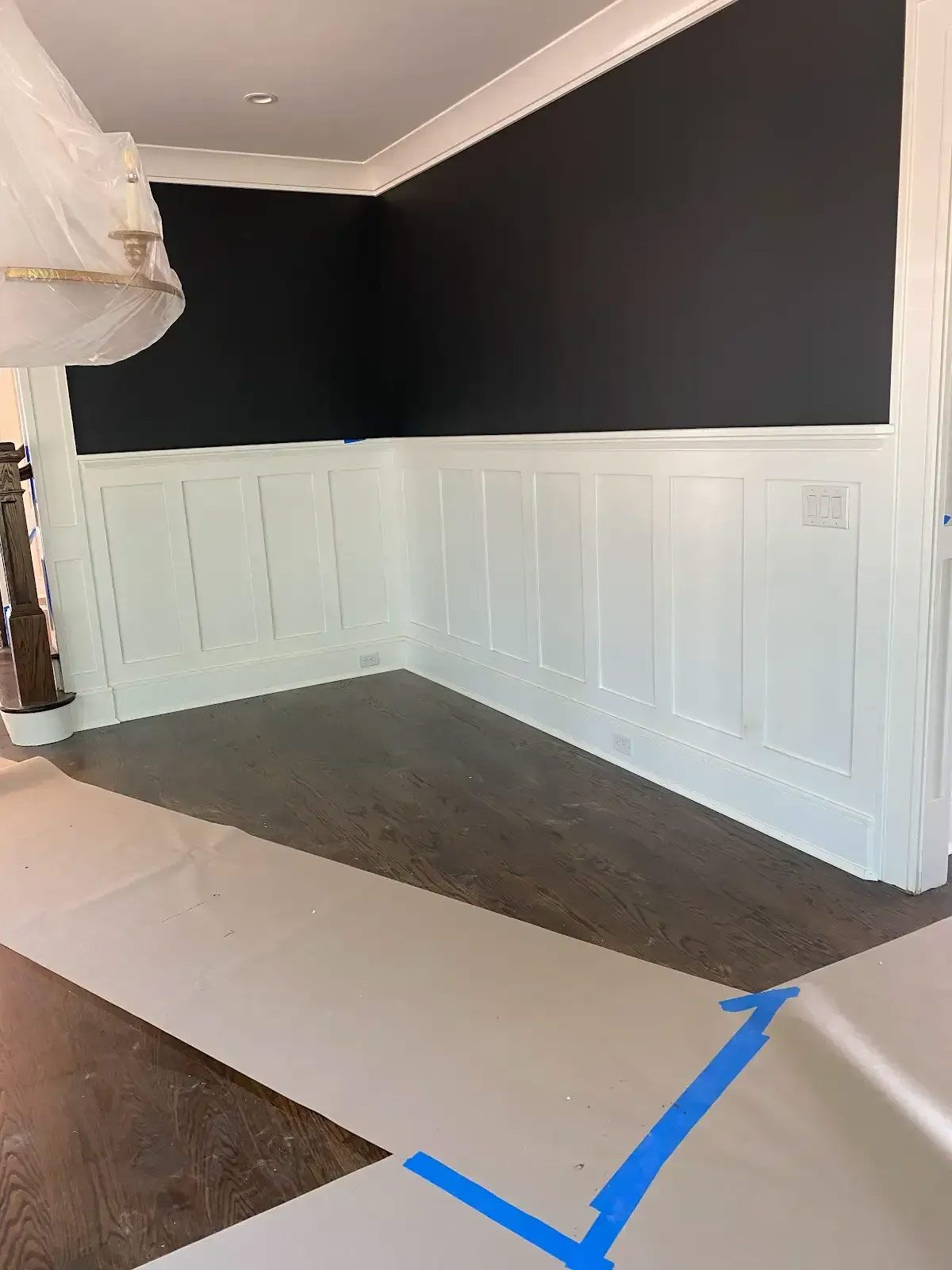 A room with black walls and white trim is being painted