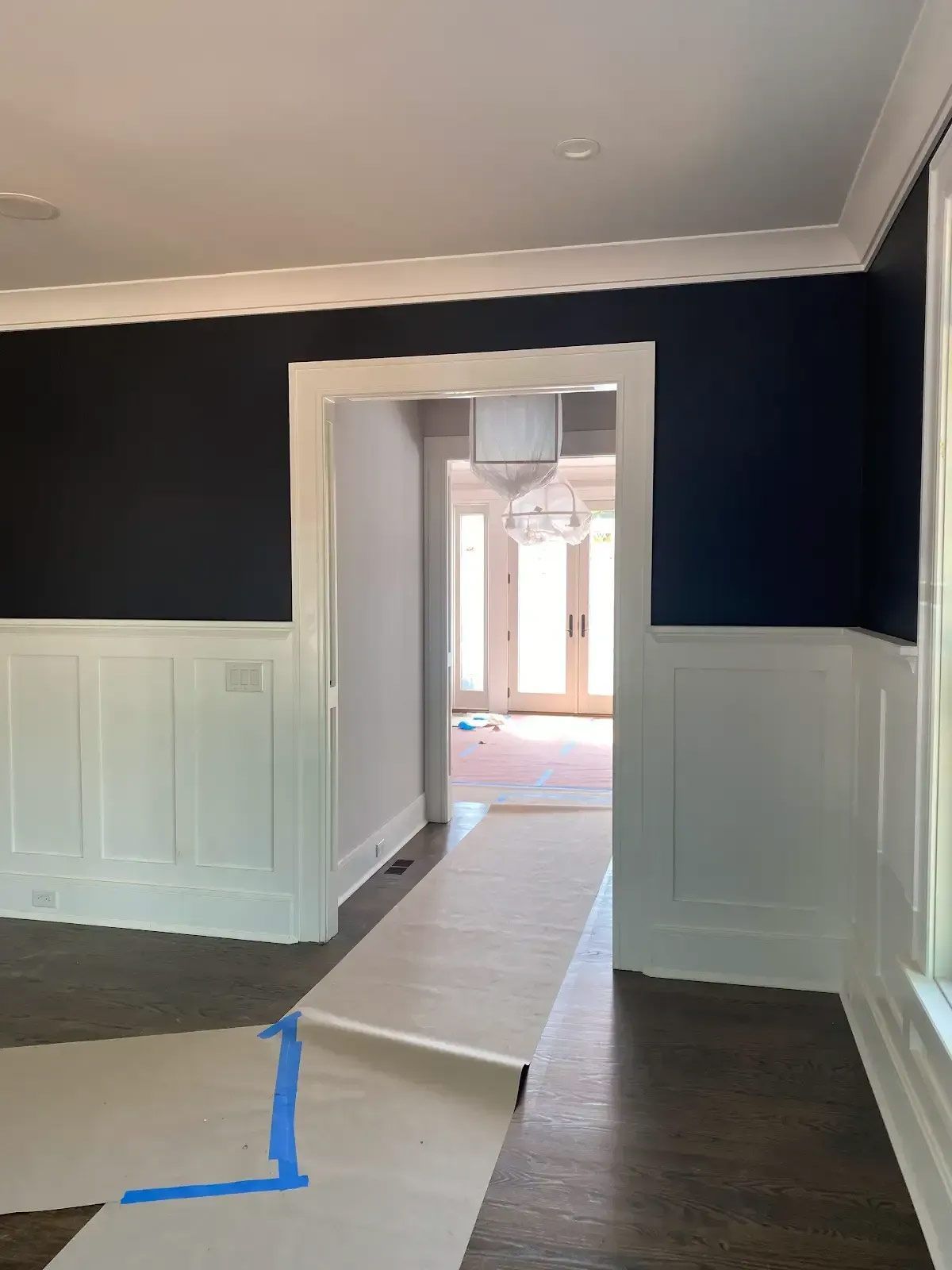 An empty room with dark blue walls and white trim