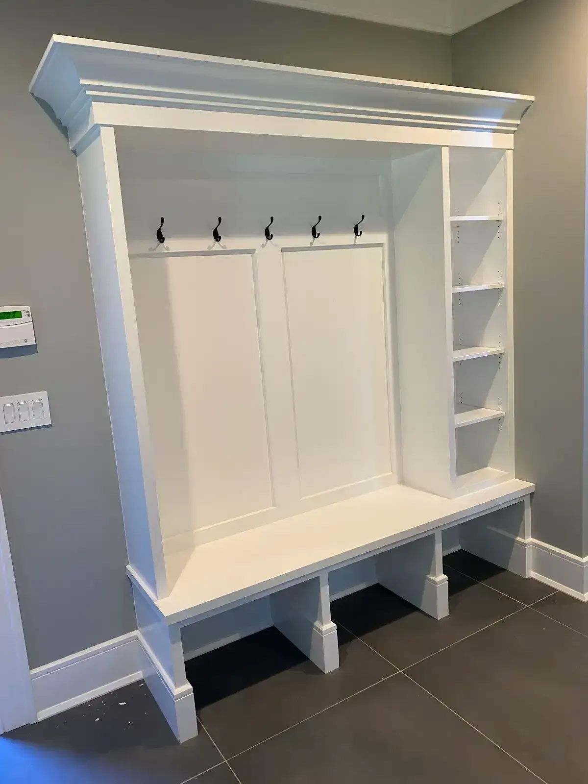 A white bench with hooks and shelves in a hallway