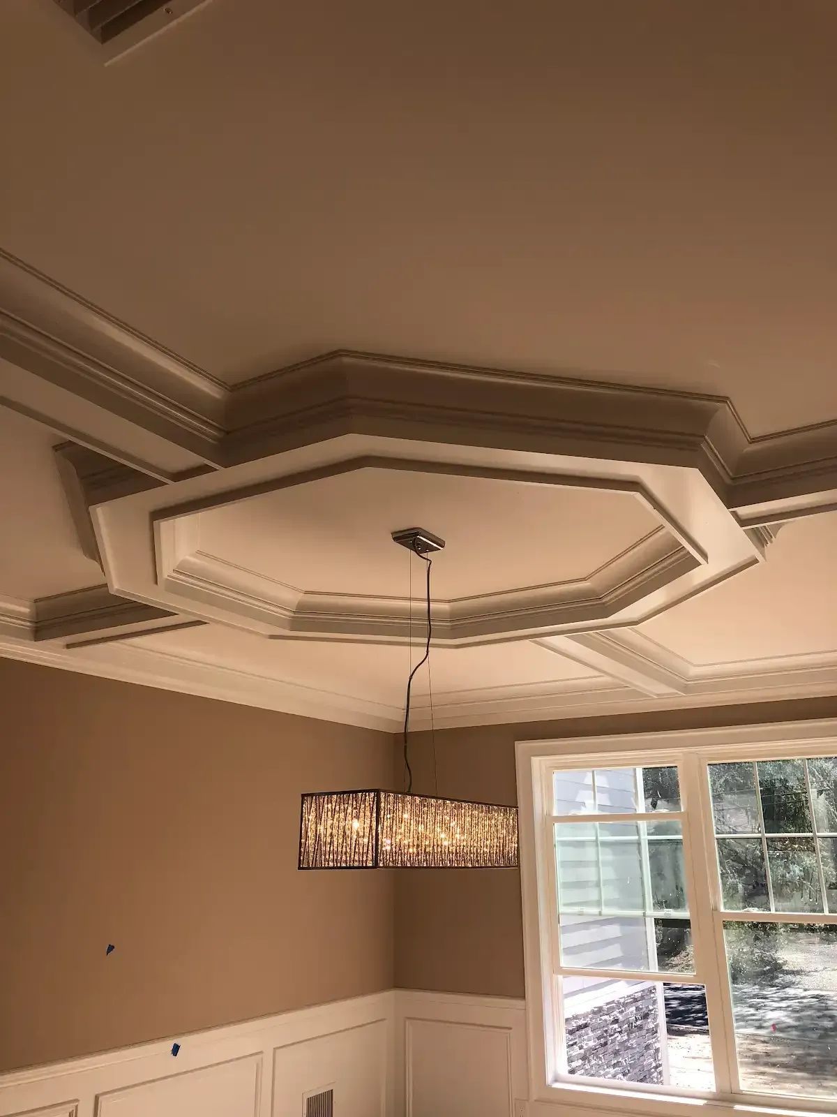 A dining room with a chandelier hanging from the ceiling and a window