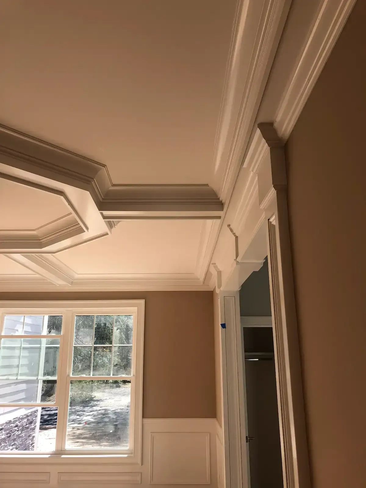 A room with a ceiling molding and a window