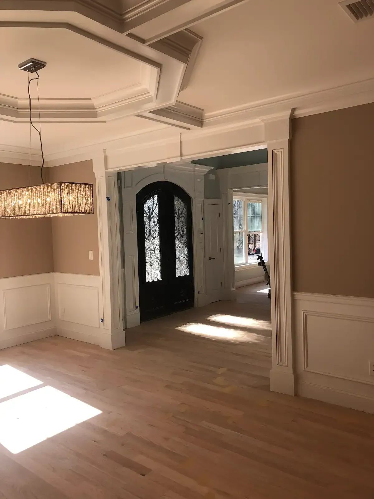 An empty living room with hardwood floors and a chandelier hanging from the ceiling