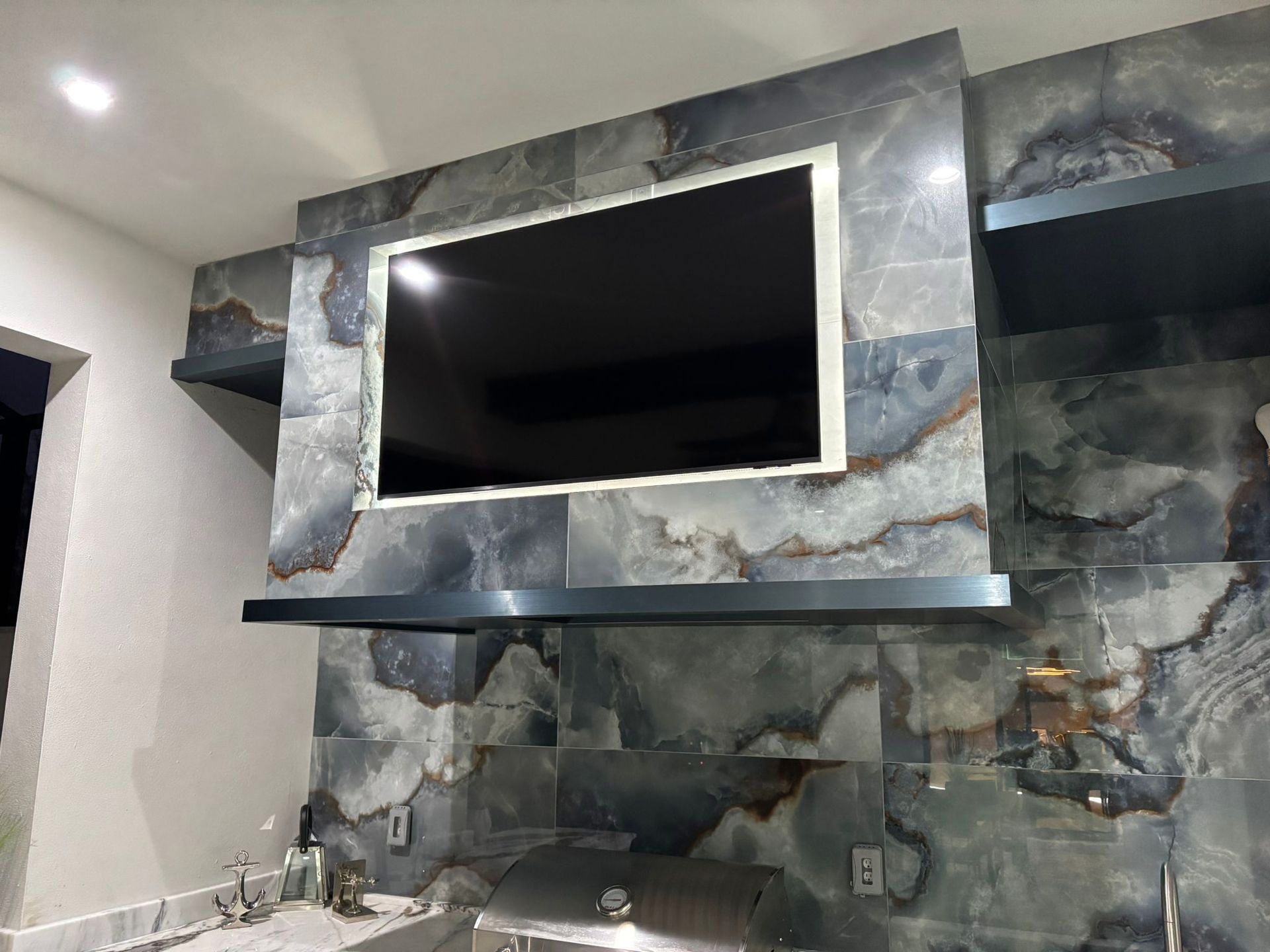A flat screen tv is mounted on a wall in a kitchen