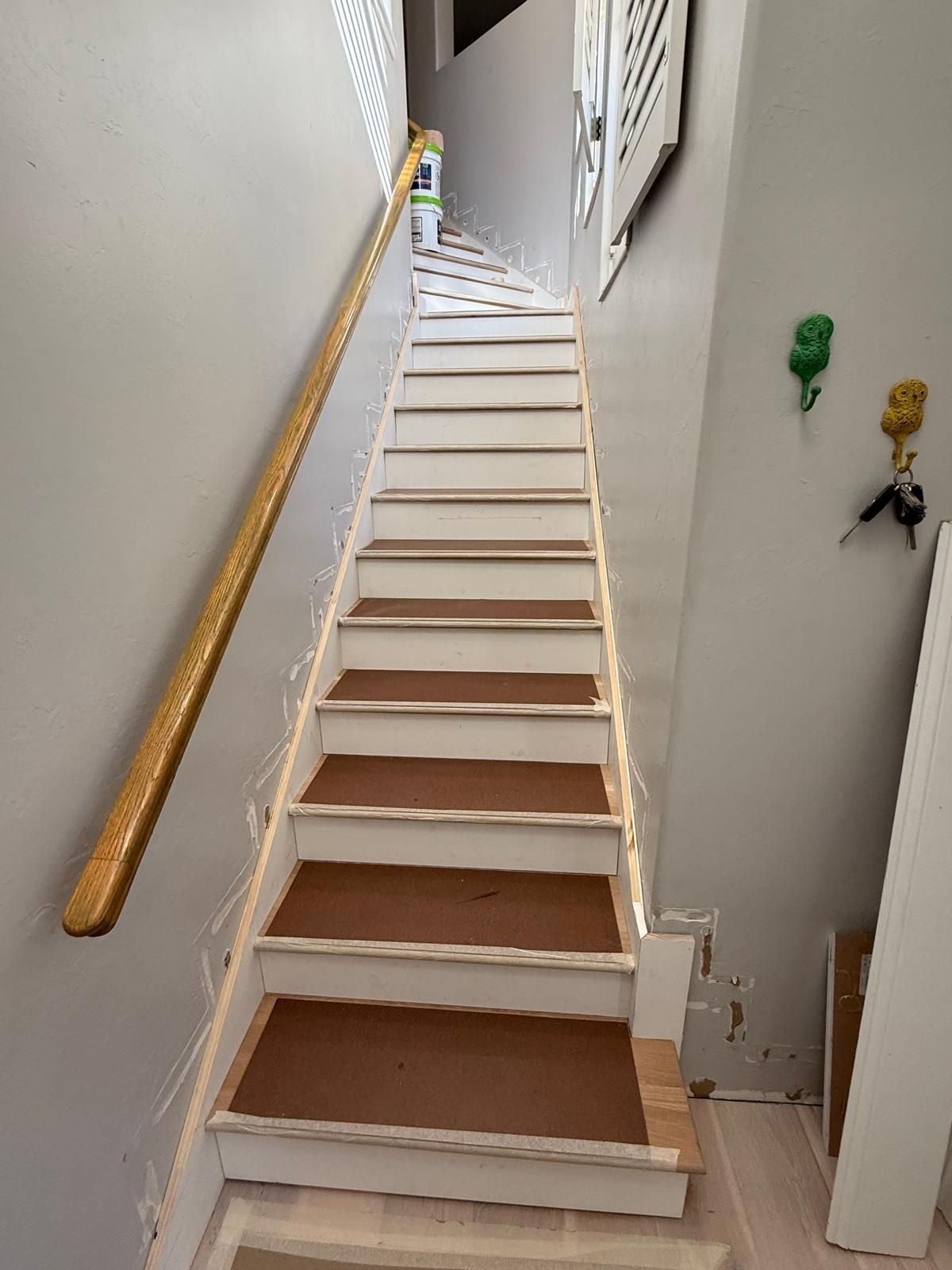 A set of white stairs with brown steps and a wooden railing