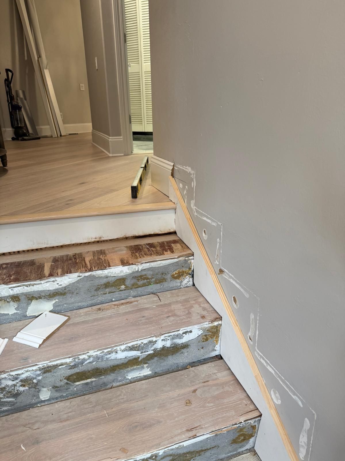 A wooden railing is being installed on a set of stairs