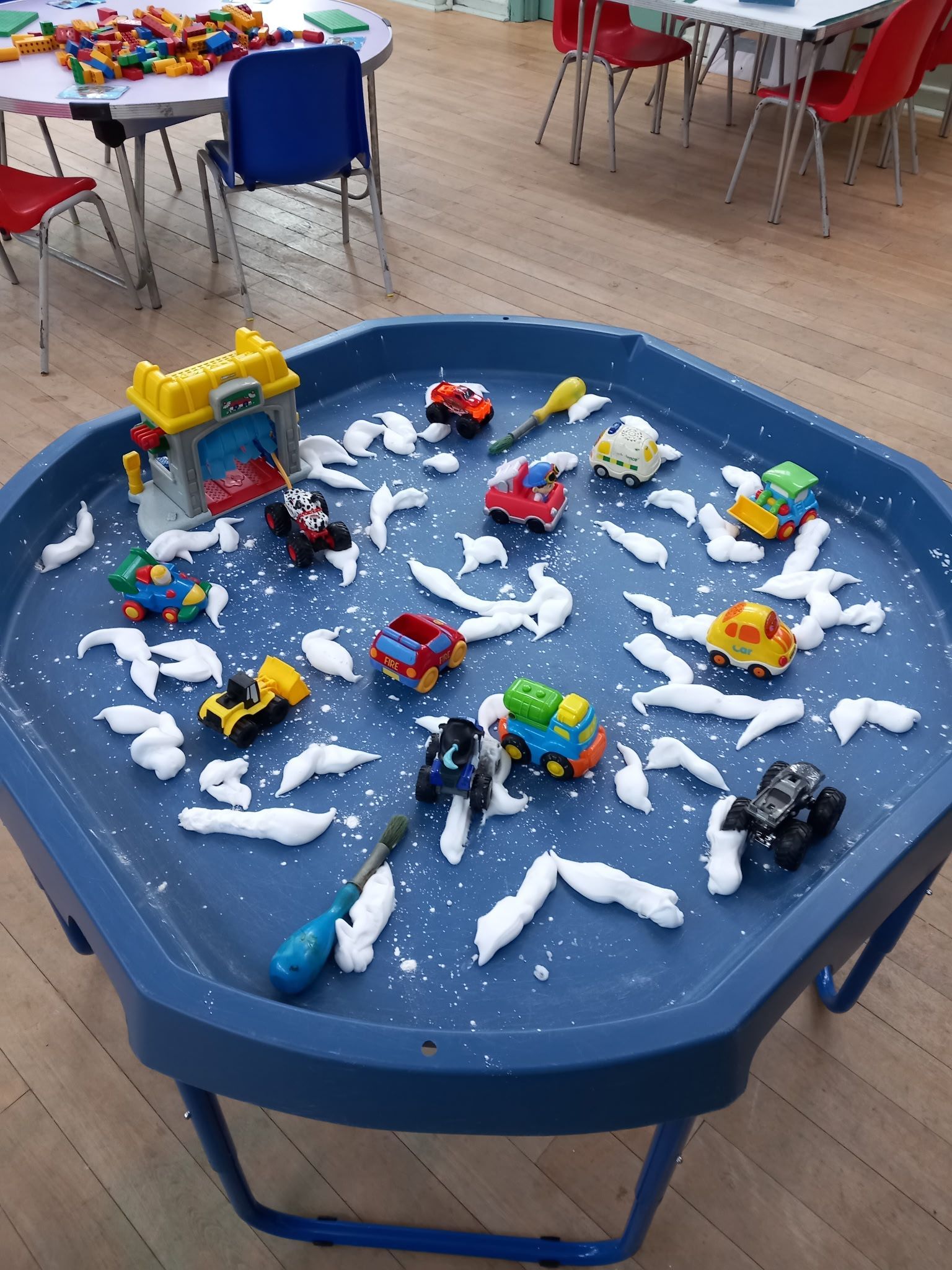 A blue sensory bin with toy cars in 