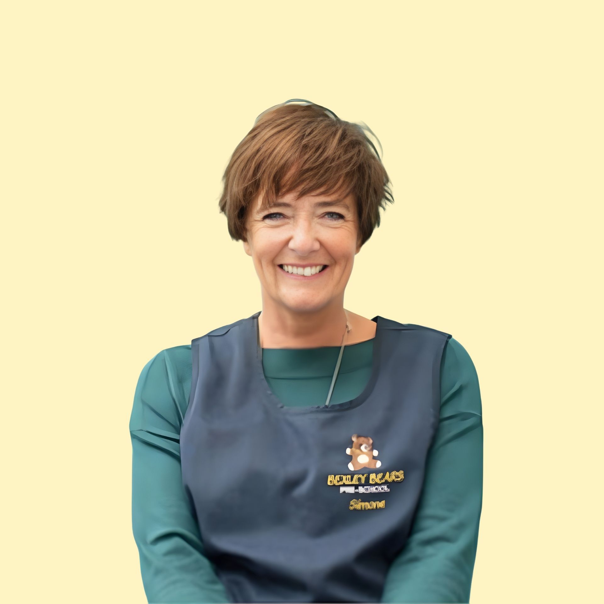 Man with dark hair and beard, smiling broadly, holding a pen. Yellow background.