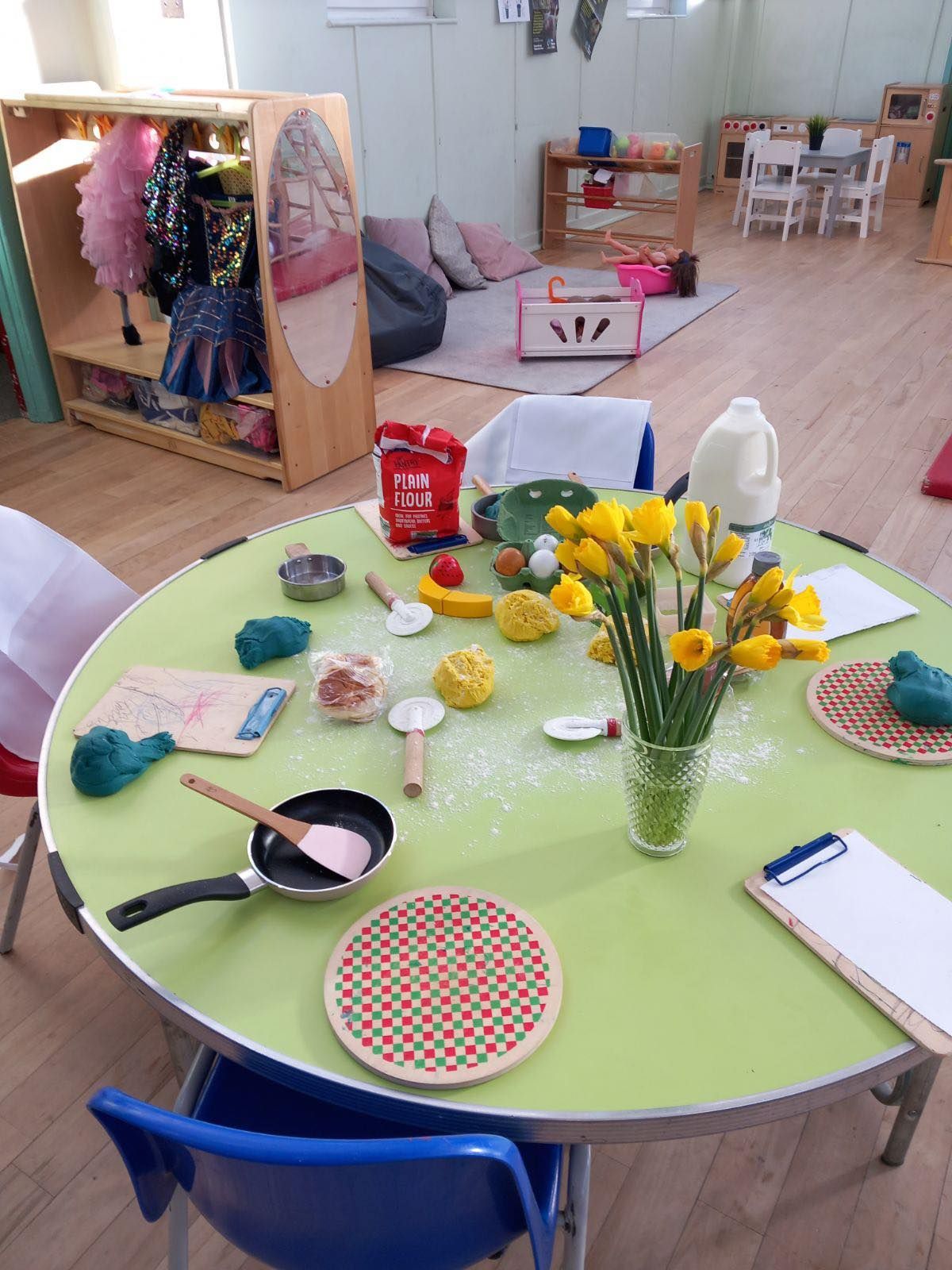 Children's play area with a round table set up for pretend cooking.  