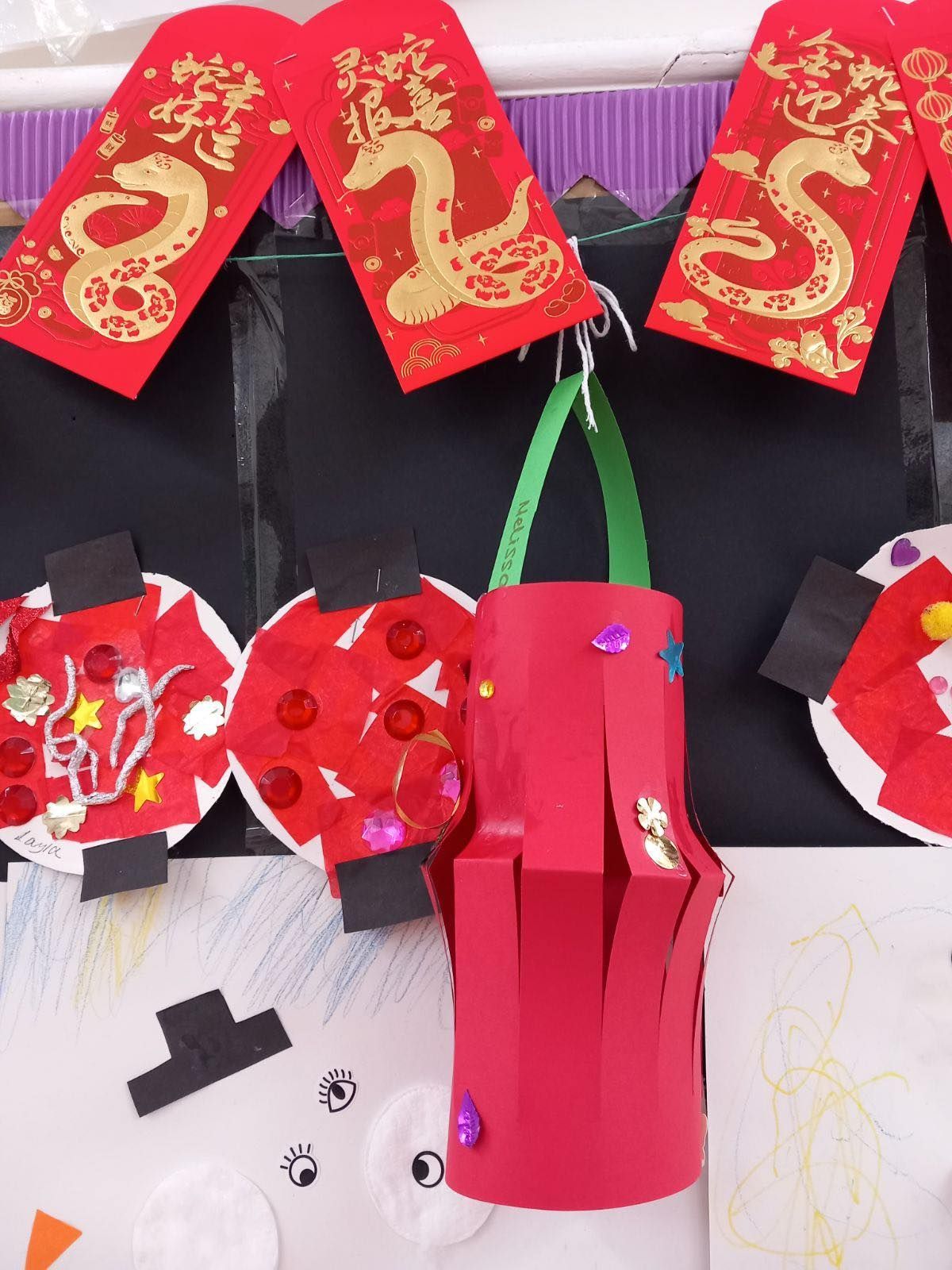 Red paper lanterns, envelopes, and craft decorations against a black and white background.