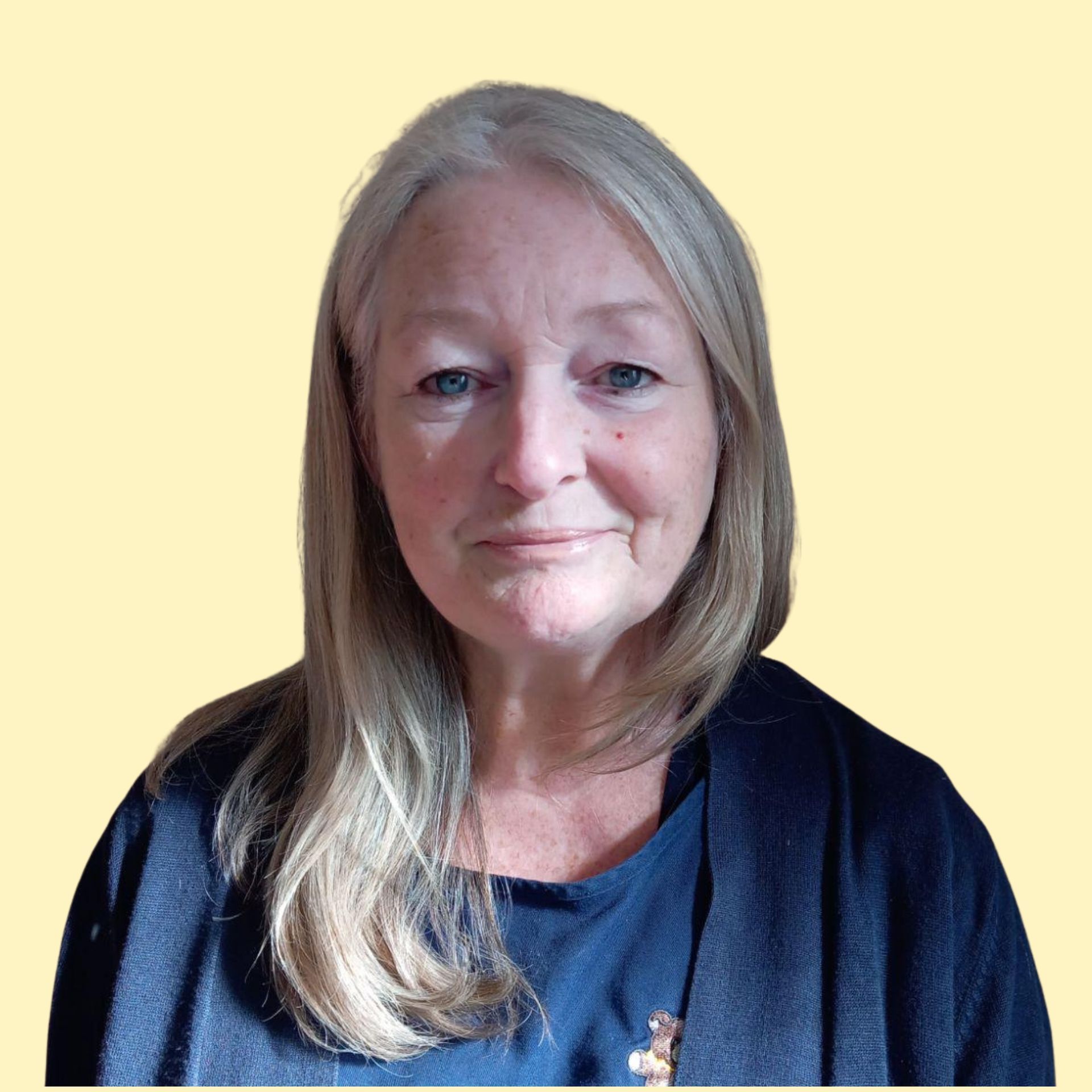 Blonde woman smiling broadly against a yellow background, wearing a white top.