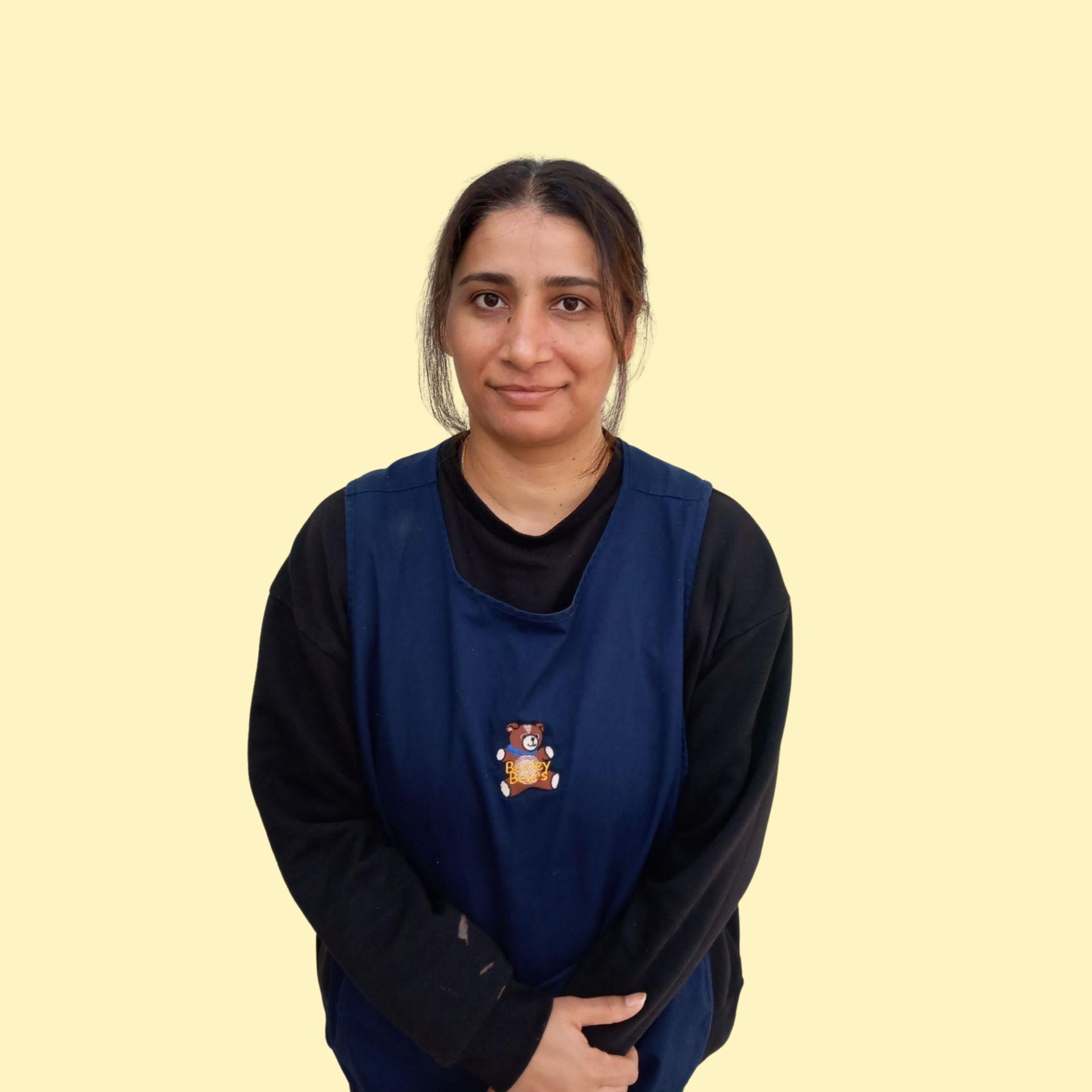 Blonde woman smiling broadly against a yellow background, wearing a white top.