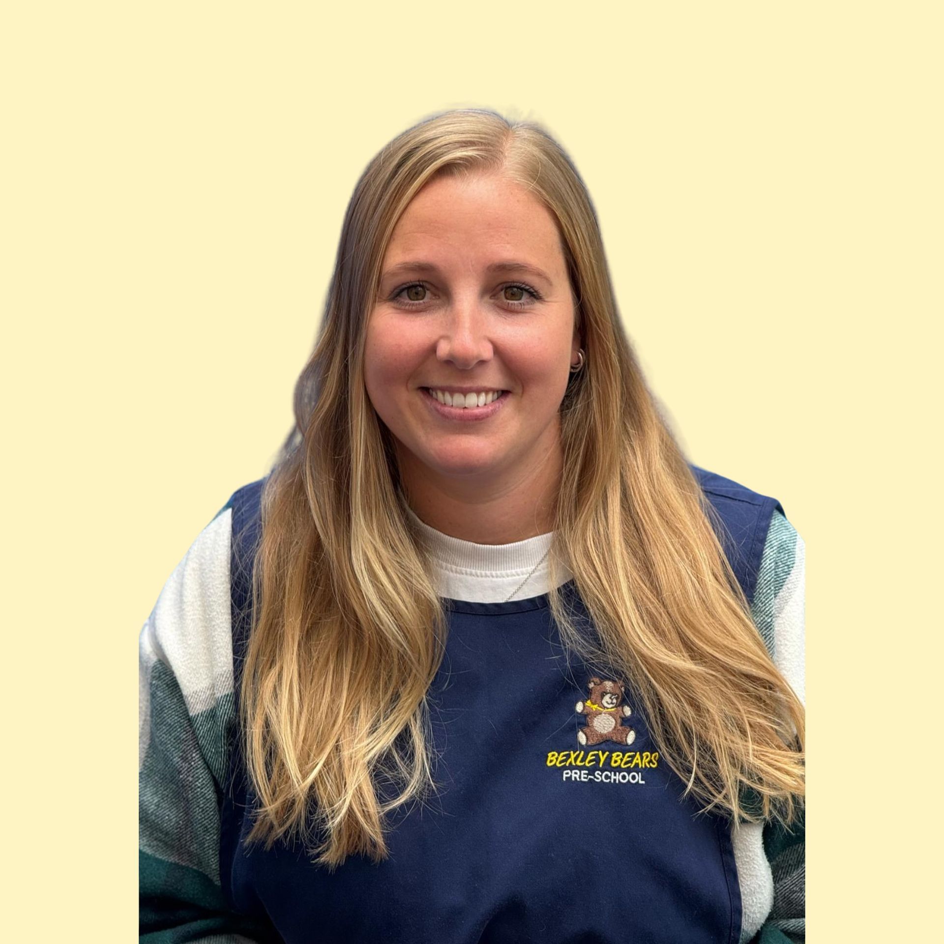 Blonde woman smiling broadly against a yellow background, wearing a white top.