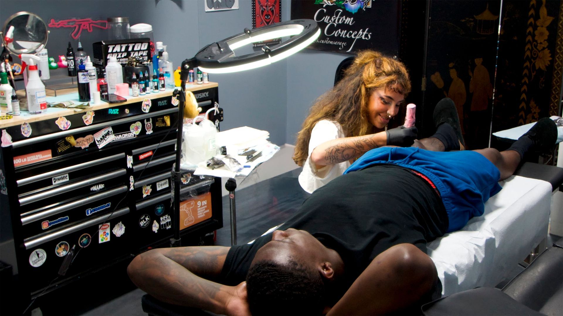 Tattoo artist using a tattoo machine on a client’s arm in a studio