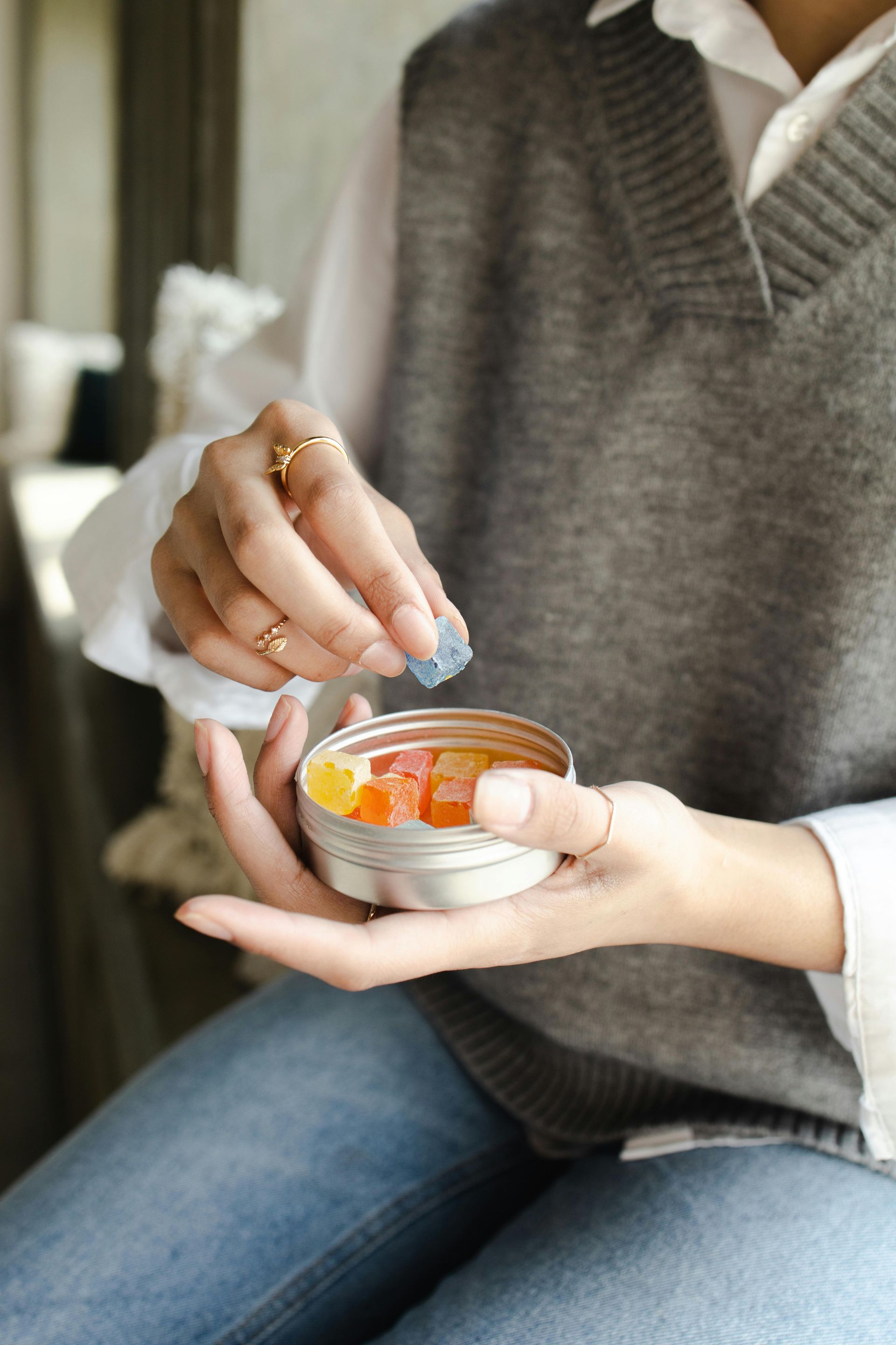 A woman is holding a tin of gummy bears in her hand.