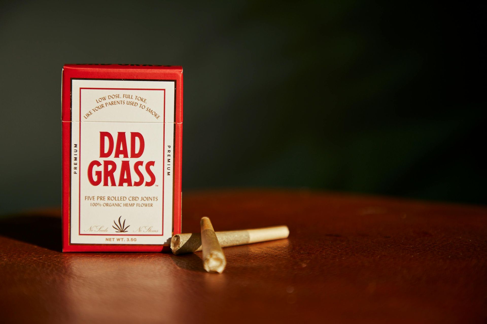 A box of dad grass cigarettes is sitting on a wooden table.