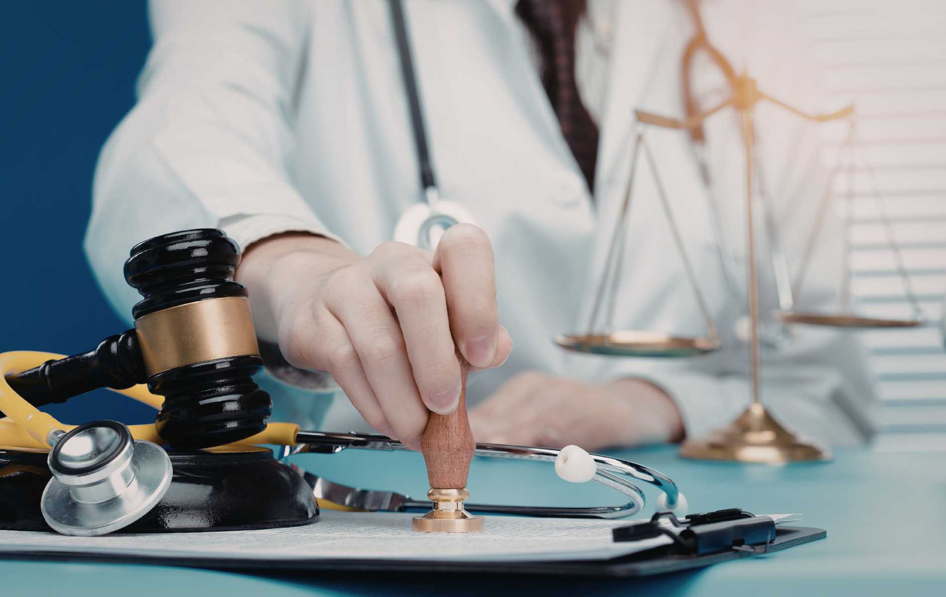 A medical professional in a white coat stamping a document beside a wooden gavel, stethoscope, and scales of justice.