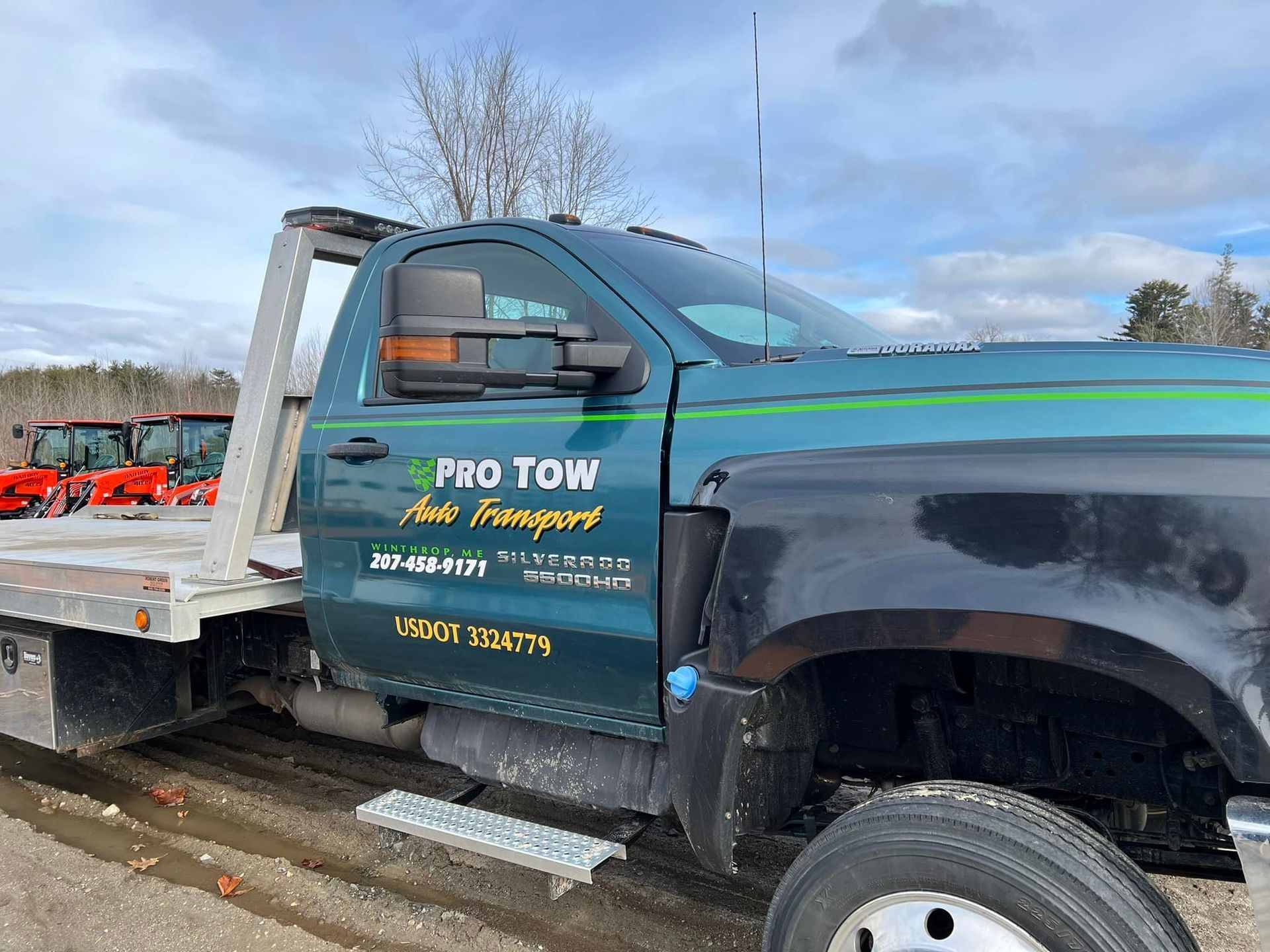 A green and black tow truck is parked on the side of the road.