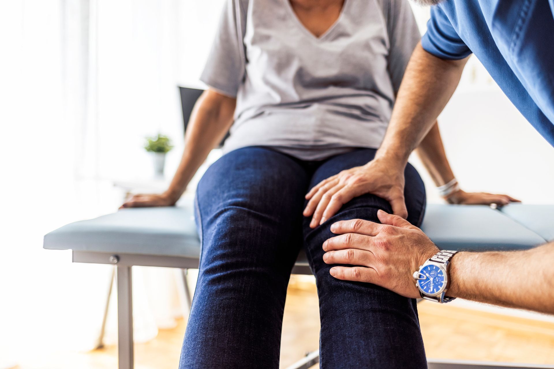 A woman is sitting on a table while a doctor examines her knee — Chiropractic Care in Idaho Falls, ID