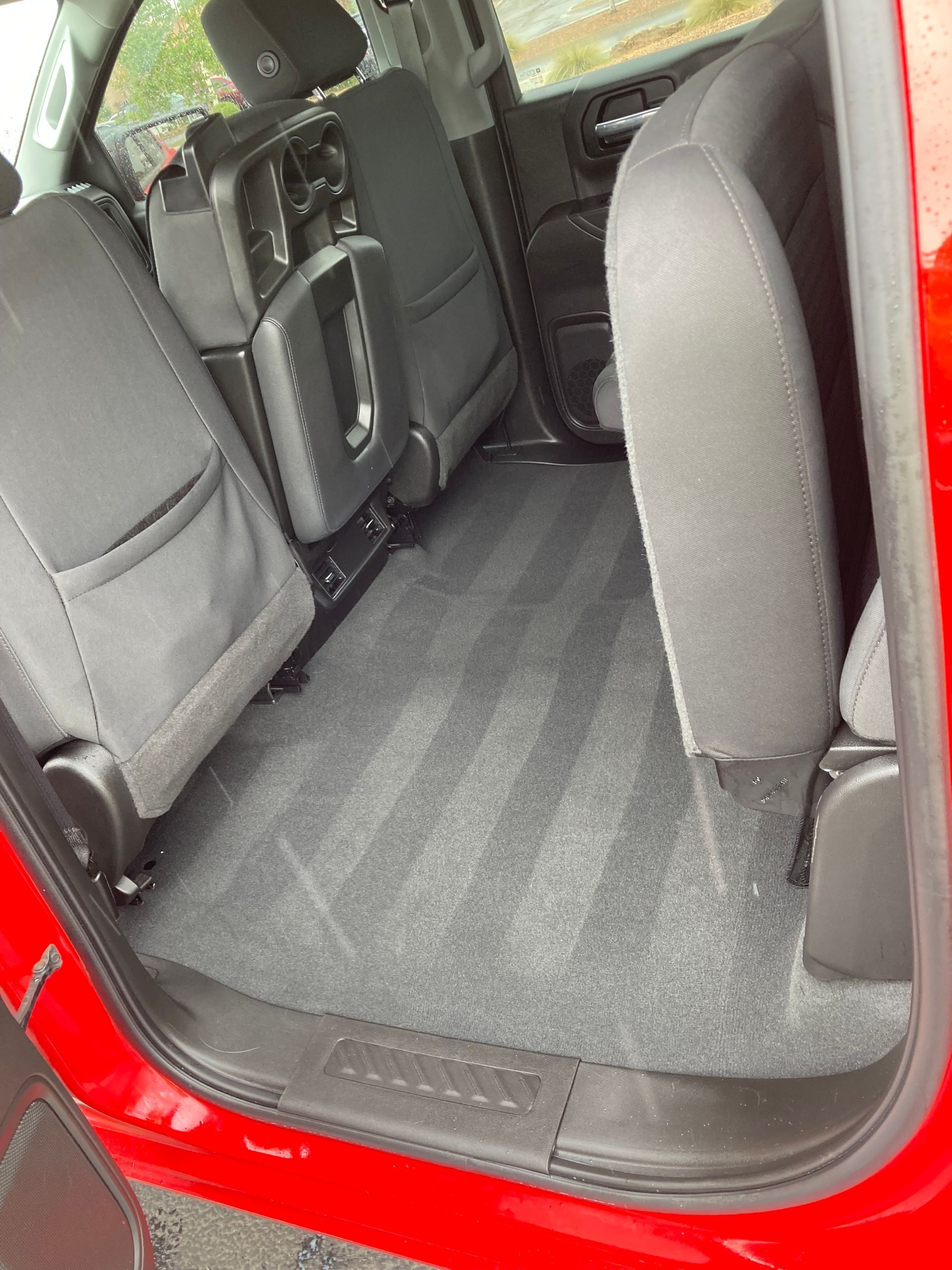 The back seat of a red truck with the door open